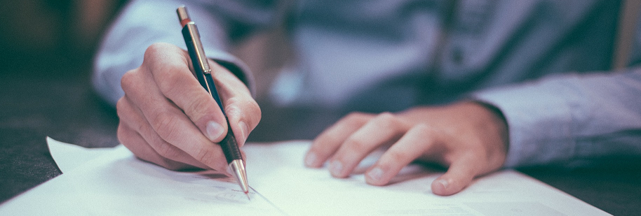 person writing on white paper with pen