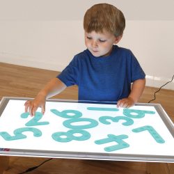 child organising blue translucent numbers on light table