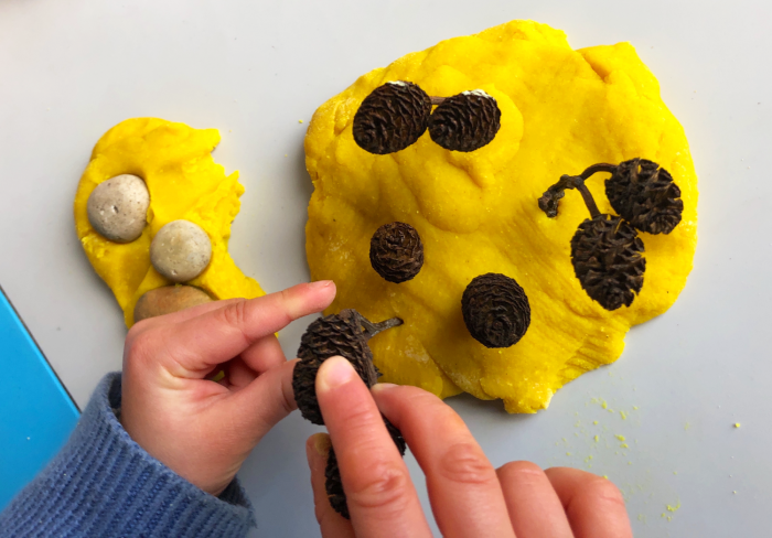 child putting natural resources into play dough