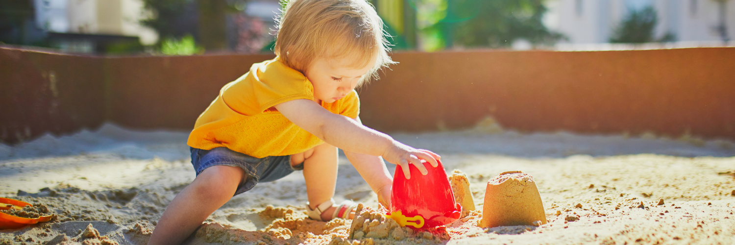 child using sand bucket to make sand structures