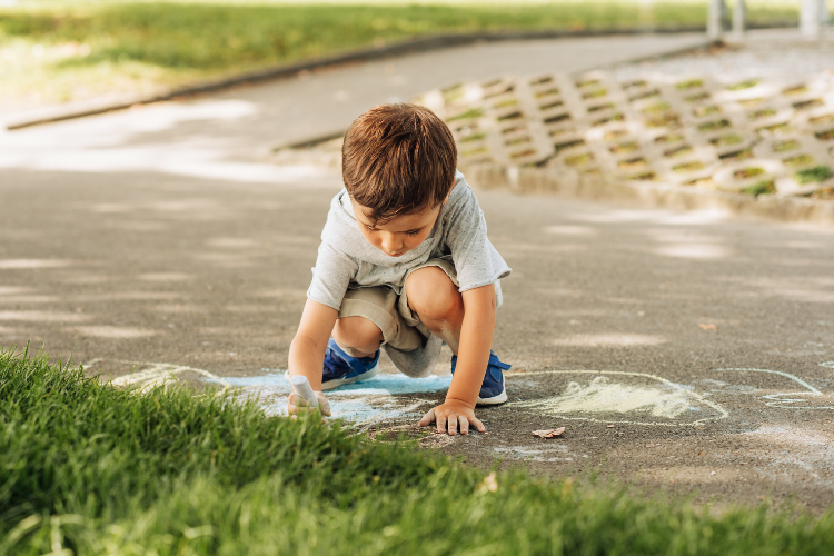 child drawing on floor with chalk