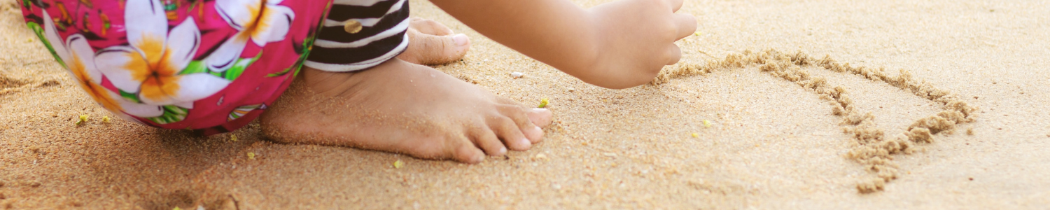 child tracing shapes into sand