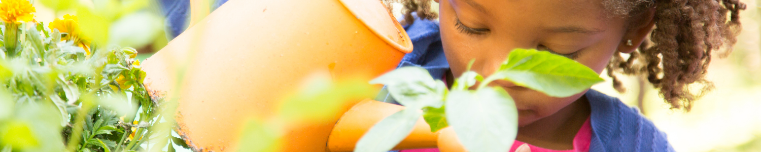 child watering plants with yellow flower watering pot