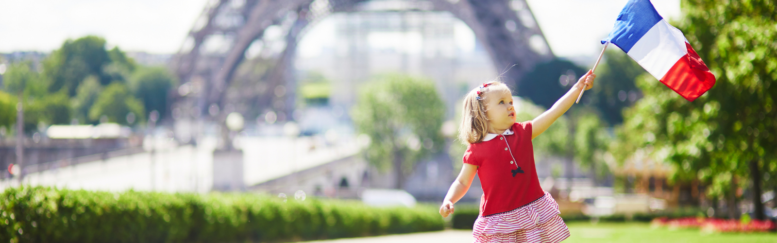 child holding a french flag outside of the eiffel tower