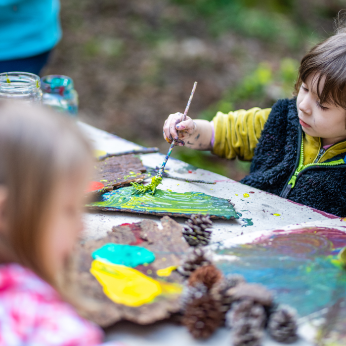 children painting on tree bark with green and yellow paint