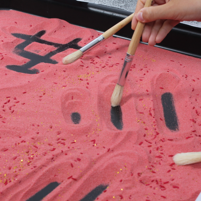 using paintbrush to make marks in sand