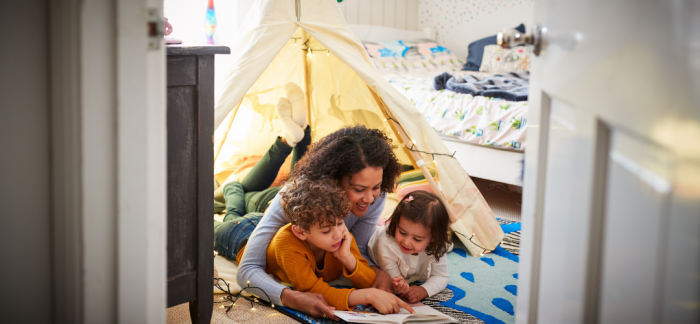 Mother reading to her two children in a homemade den