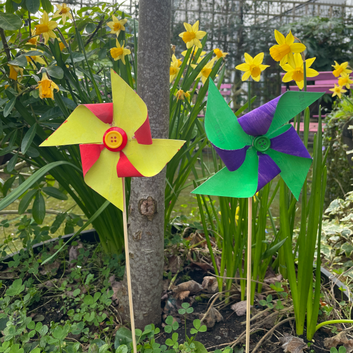 two coloured paper windmills outside